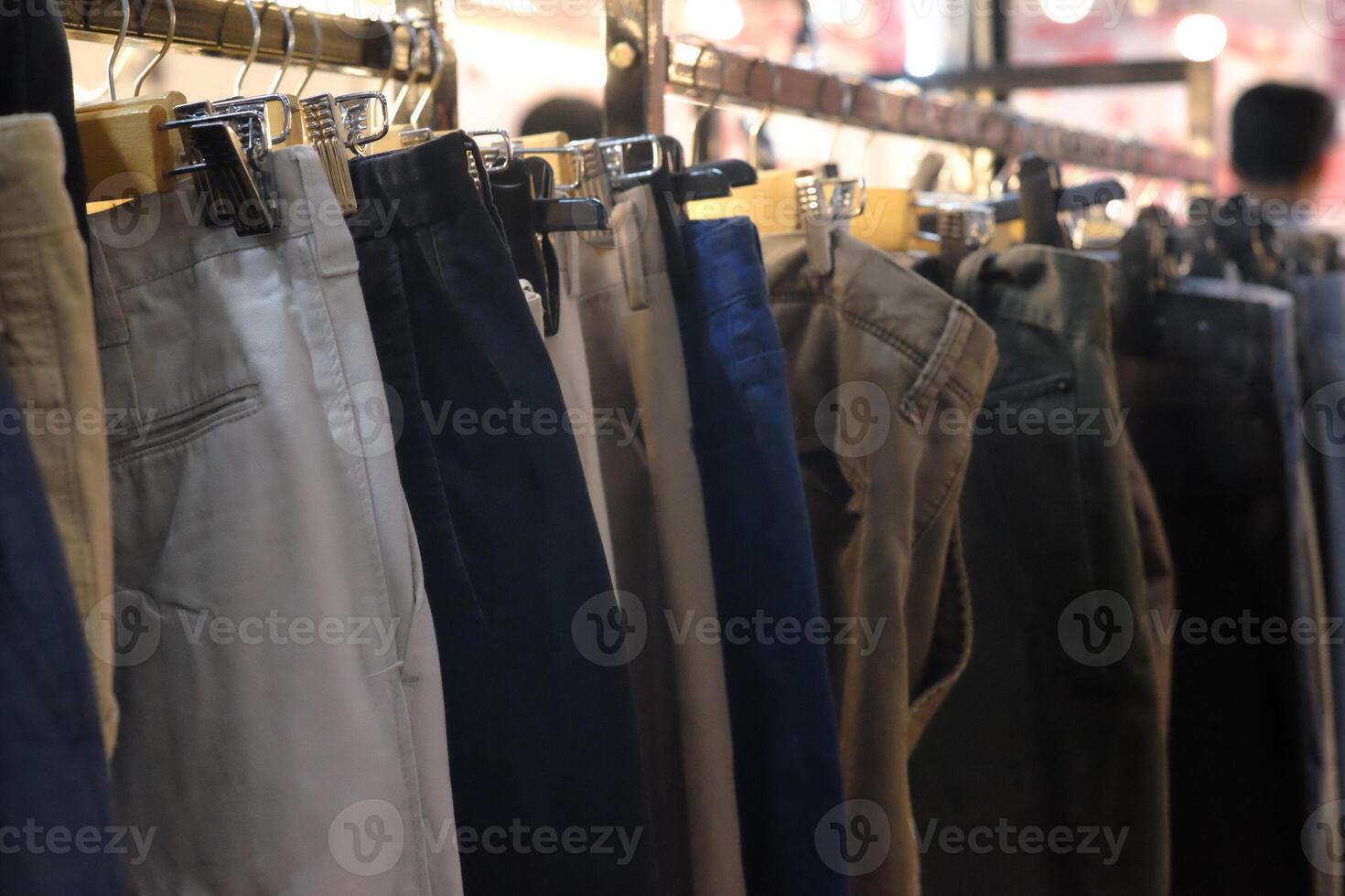 Thrifting's vibrant collection of sweaters, shirts, hoodies, trousers and knitted t-shirts are elegantly displayed on wooden hangers, featuring a variety of colors and textures. photo
