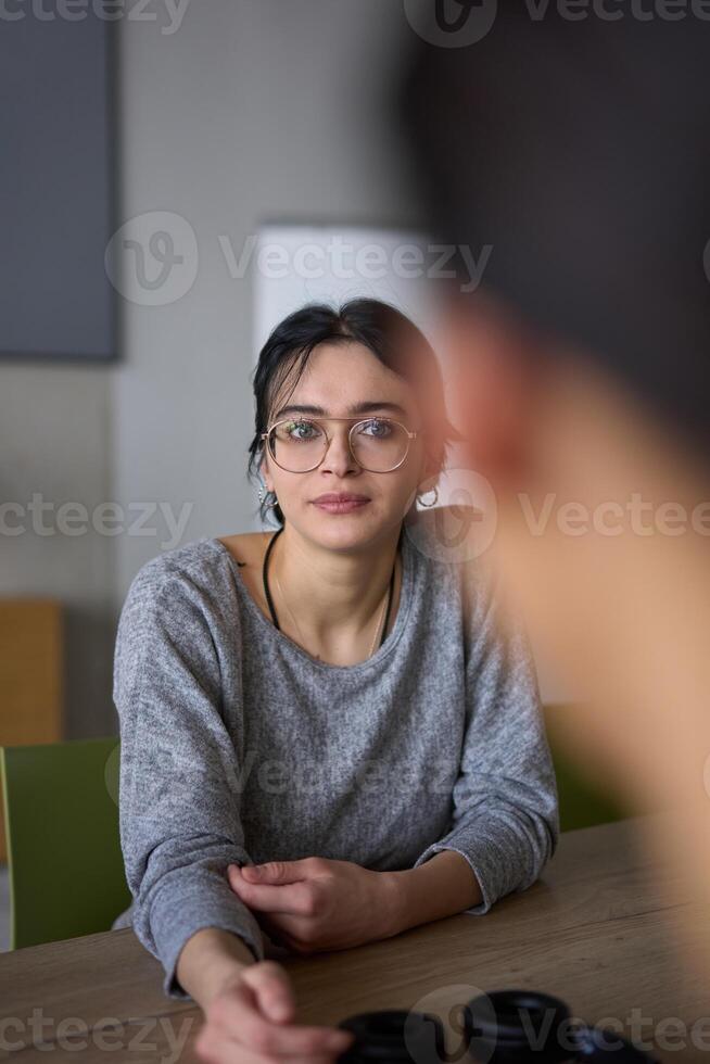 A close up portrait of a young businesswoman engaged in a professional meeting, confidently discussing ideas and strategies with her colleagues photo