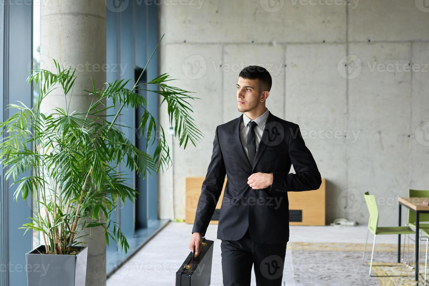 A determined businessman in a black suit confidently walks through the office, embodying professionalism and focus as he heads towards new challenges photo