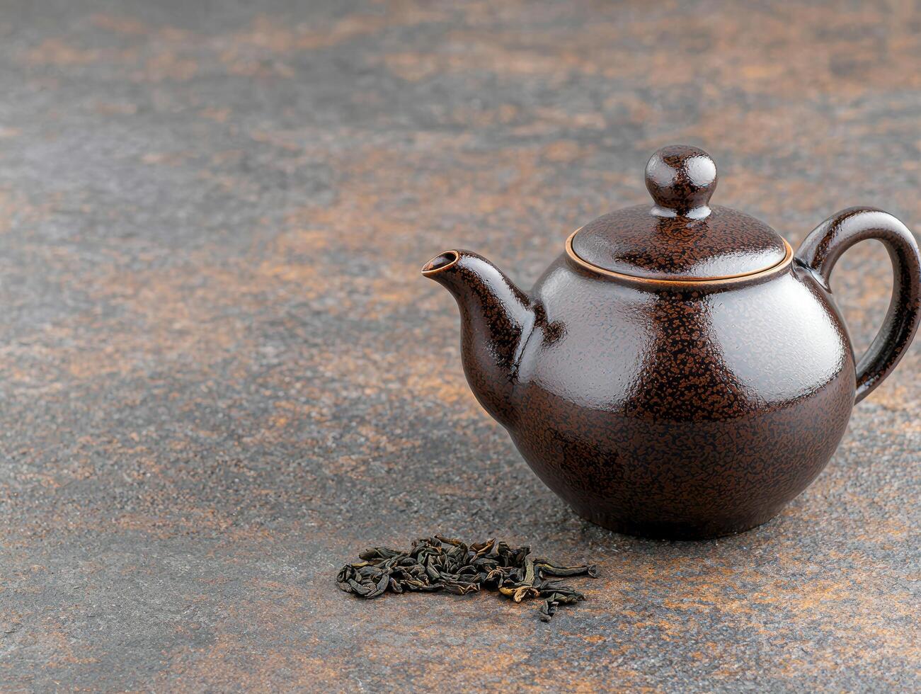 Antique ceramic teapot with dried tea leaves on stone background photo