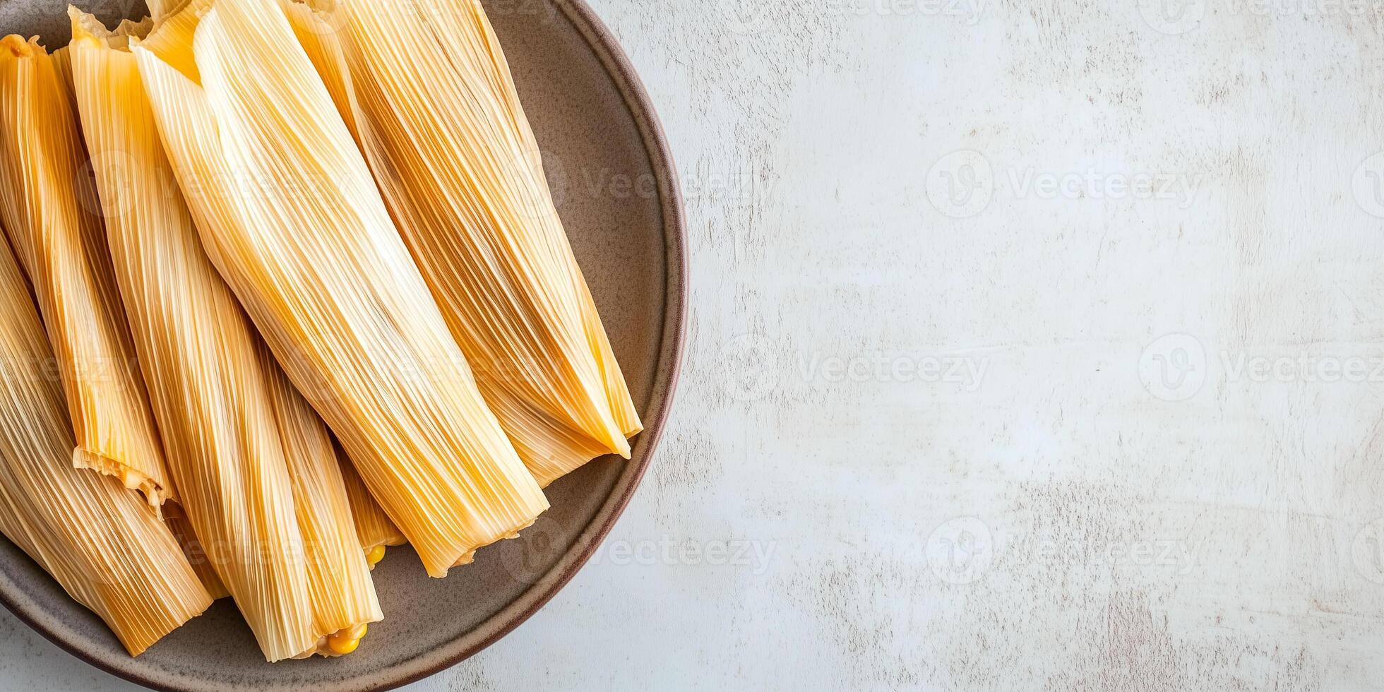 Plate of tamales with visible corn husks and a glimpse of the filling, arranged side by side, meal photography photo