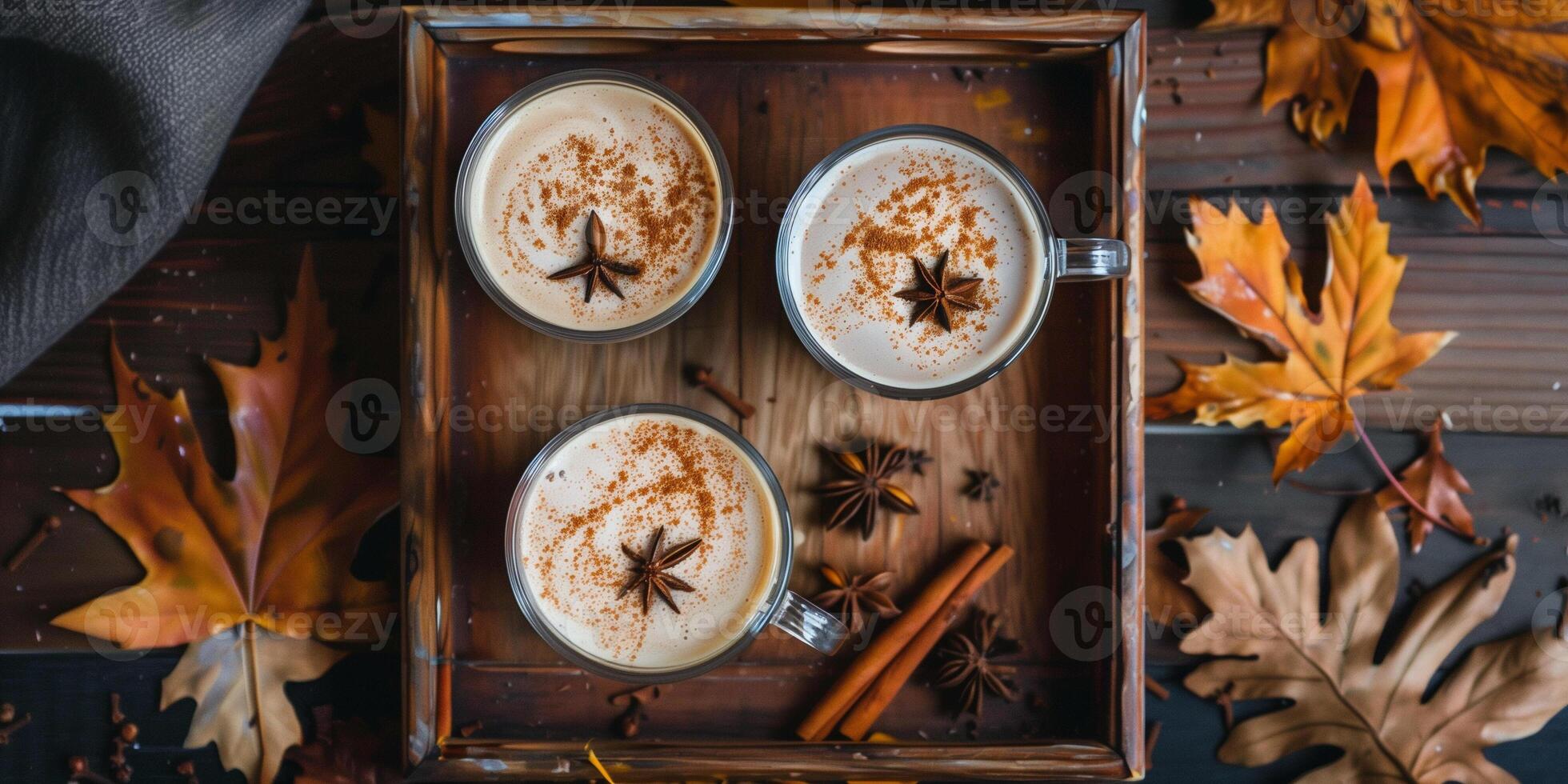 Tray holding pumpkin spice lattes in glassware, surrounded by autumn leaves and whole spices, meal photography photo