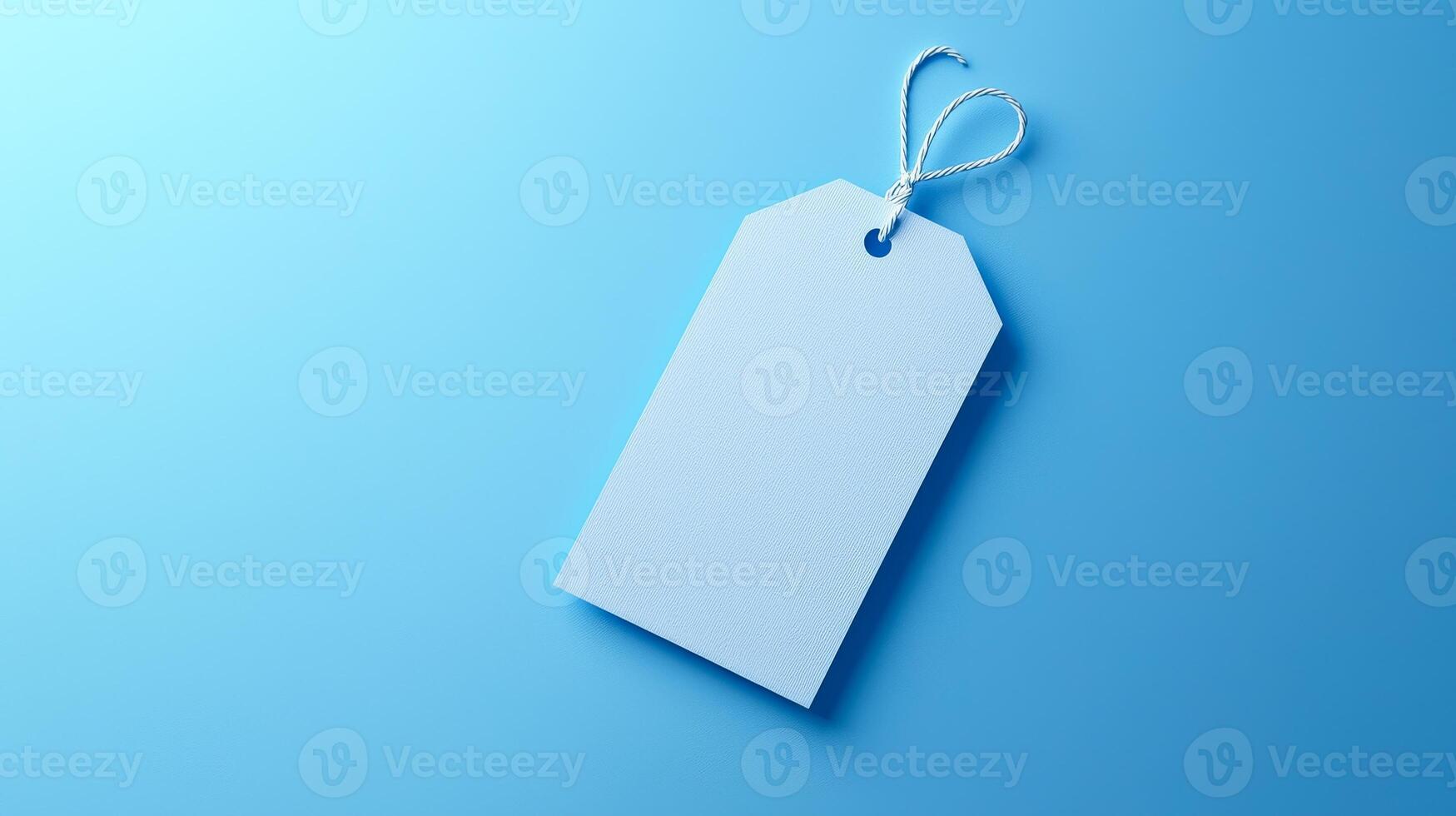A blank blue tag rests on a smooth light blue surface, ideal for labeling or pricing items artistically. photo
