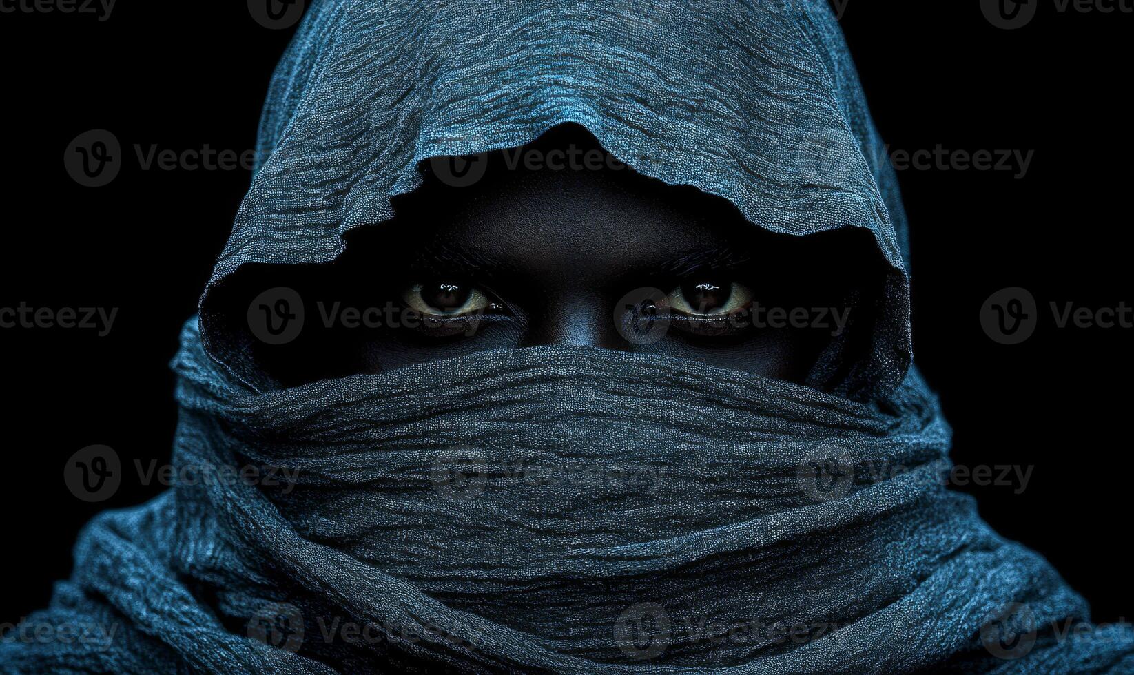 A man with a hood over his head and a black face. The hood is blue and the man's face is black photo
