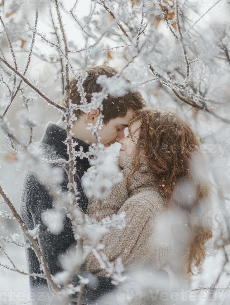 Romantic Winter Embrace A couple sharing a tender moment among snow-covered branches, capturing the warmth of love amidst a frosty landscape. photo