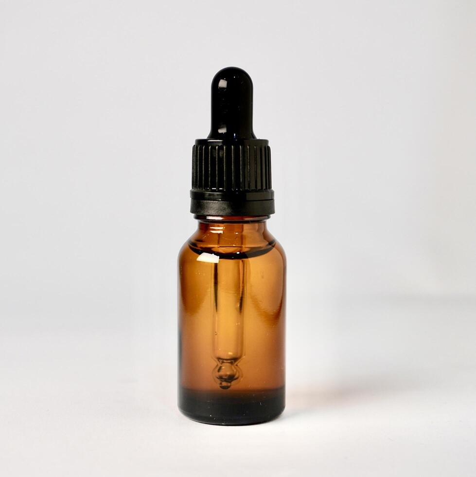 Brown transparent skin care bottle container with pipette cap isolated on square white background. photo