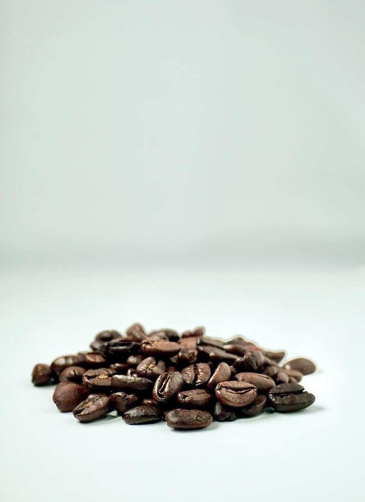 Handful of brown aromatic coffee beans isolated on vertical white background with empty copy space for text. photo