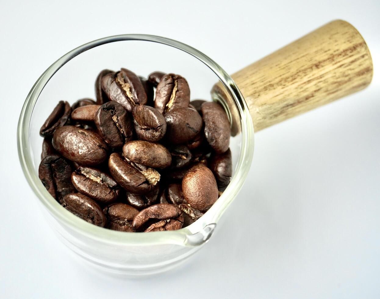 Raw coffee beans in small glass cup bowl pot container isolated on horizontal white background. photo