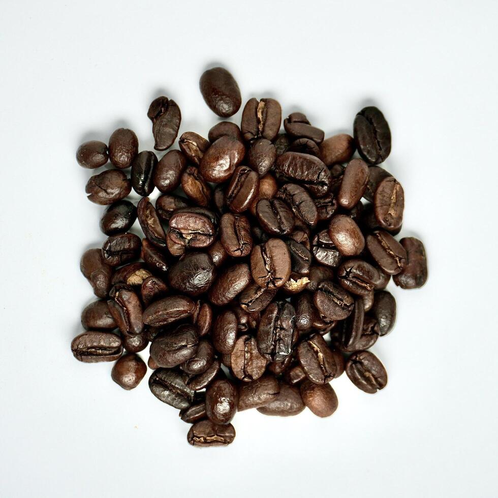 Pile of brown aromatic raw coffee beans from above angle view isolated on square white background. photo