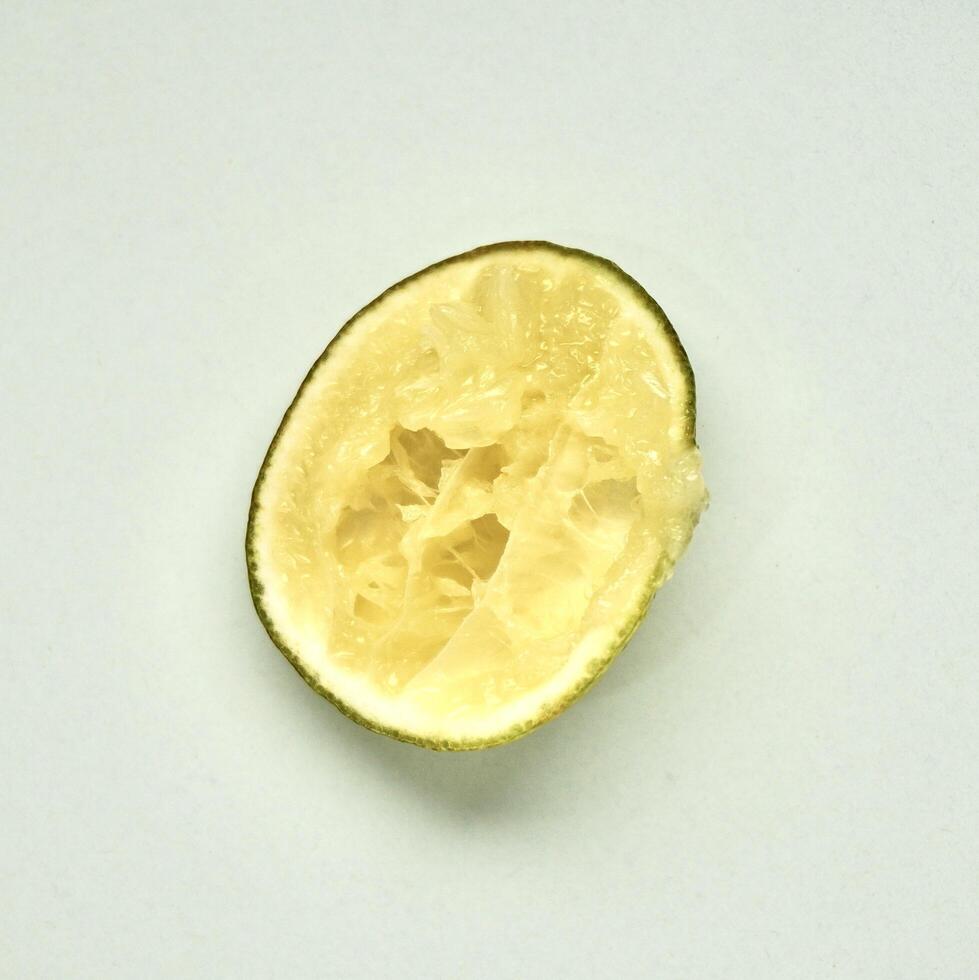 One piece of sliced in half lime citrus fruit after squeezed isolated on square white background from above angle view. photo