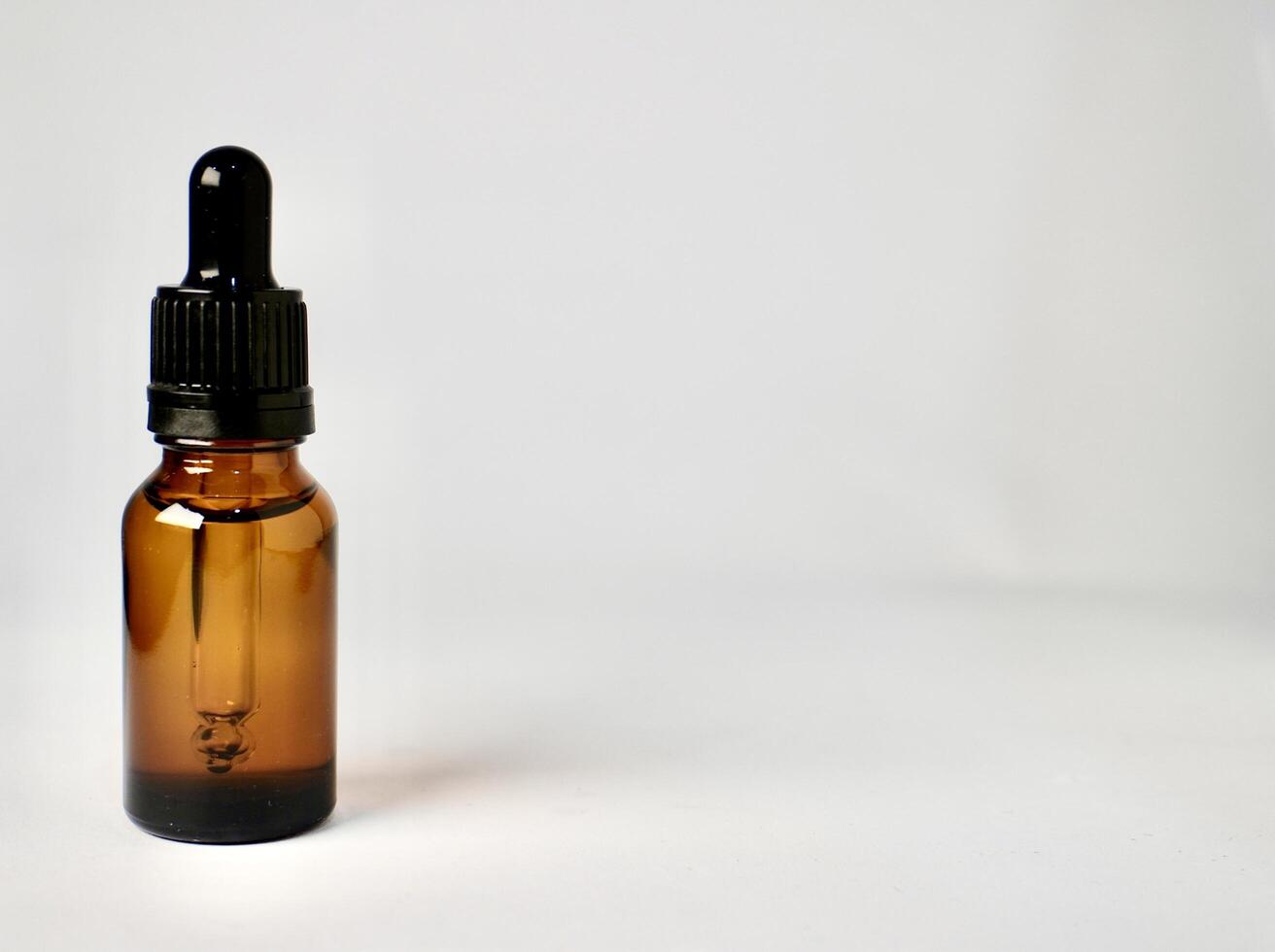 One piece of brown transparent skin care bottle container with pipette cap isolated on horizontal empty copy spaced white background. photo