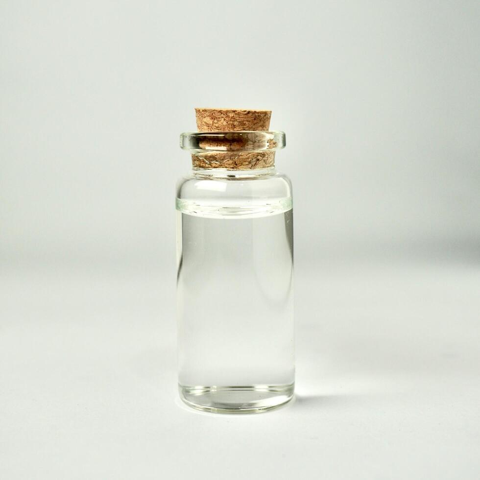 One transparent glass vial bottle container with brown cork stopper lid isolated on square white background. photo