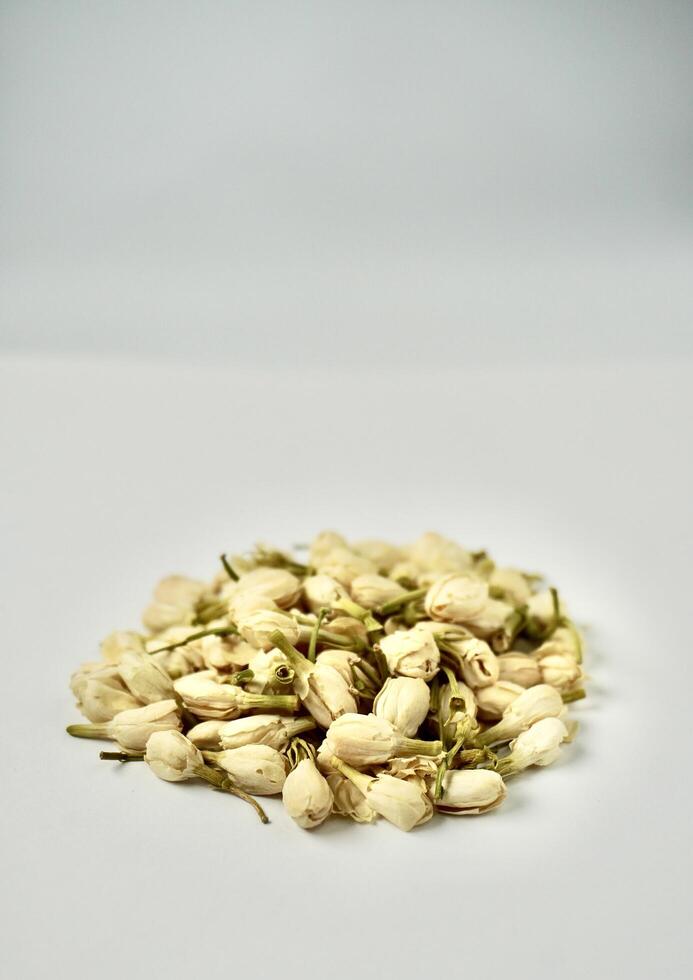 Pile of dried jasmine flower buds for aromatheraphy and tea ingredients isolated on vertical copy spaced plain background. photo