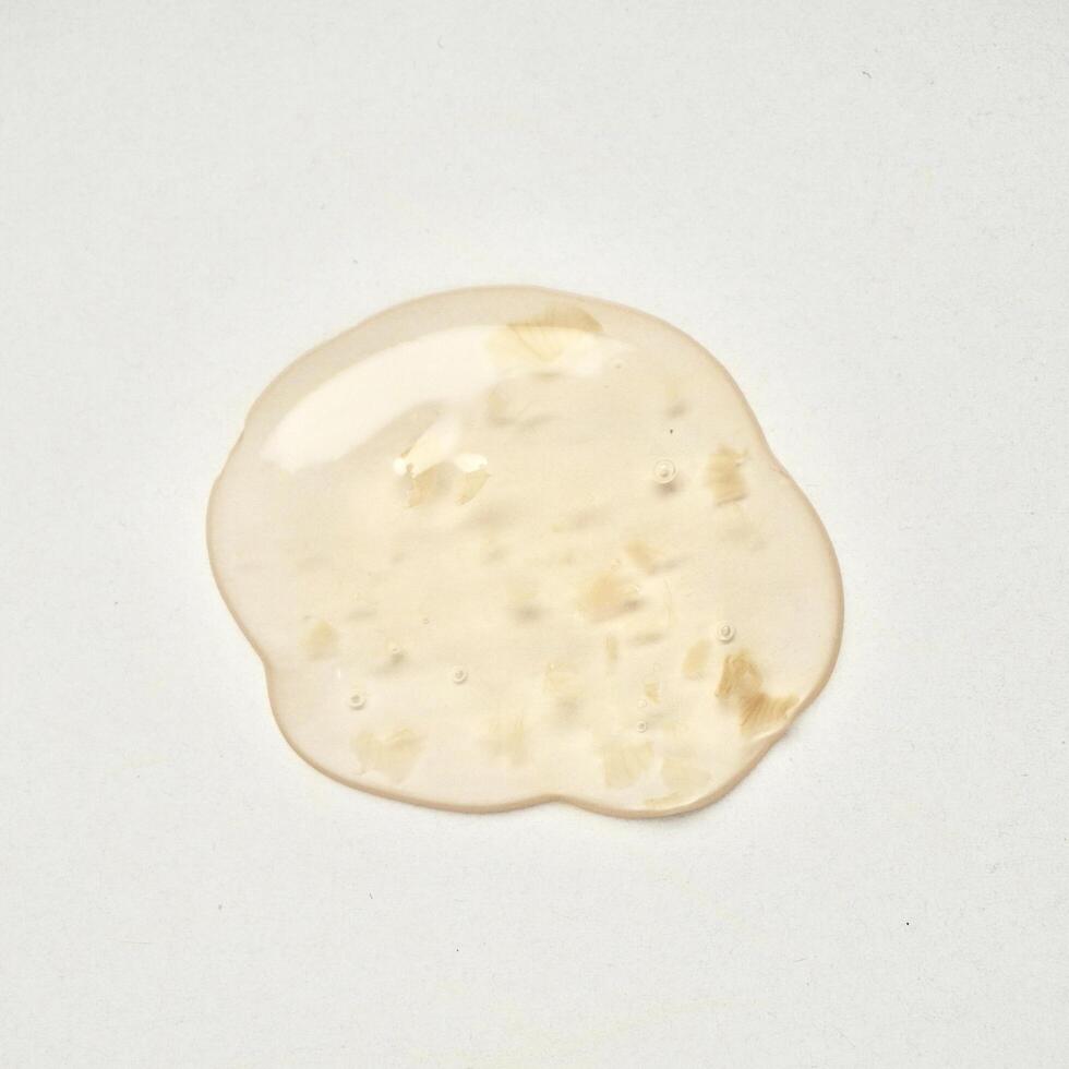 Yellow orange transparent liquid soap body care drop texture isolated on square white background from above angle view. photo