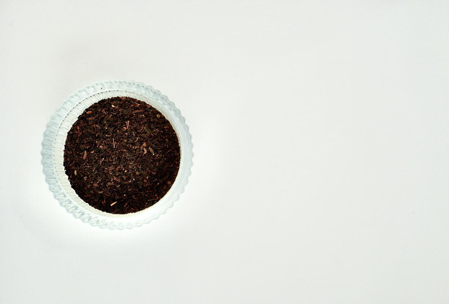 Pile of fragrant earl grey organic tea leaves in round glass bowl isolated on horizontal copy spaced white background from above angle view. photo