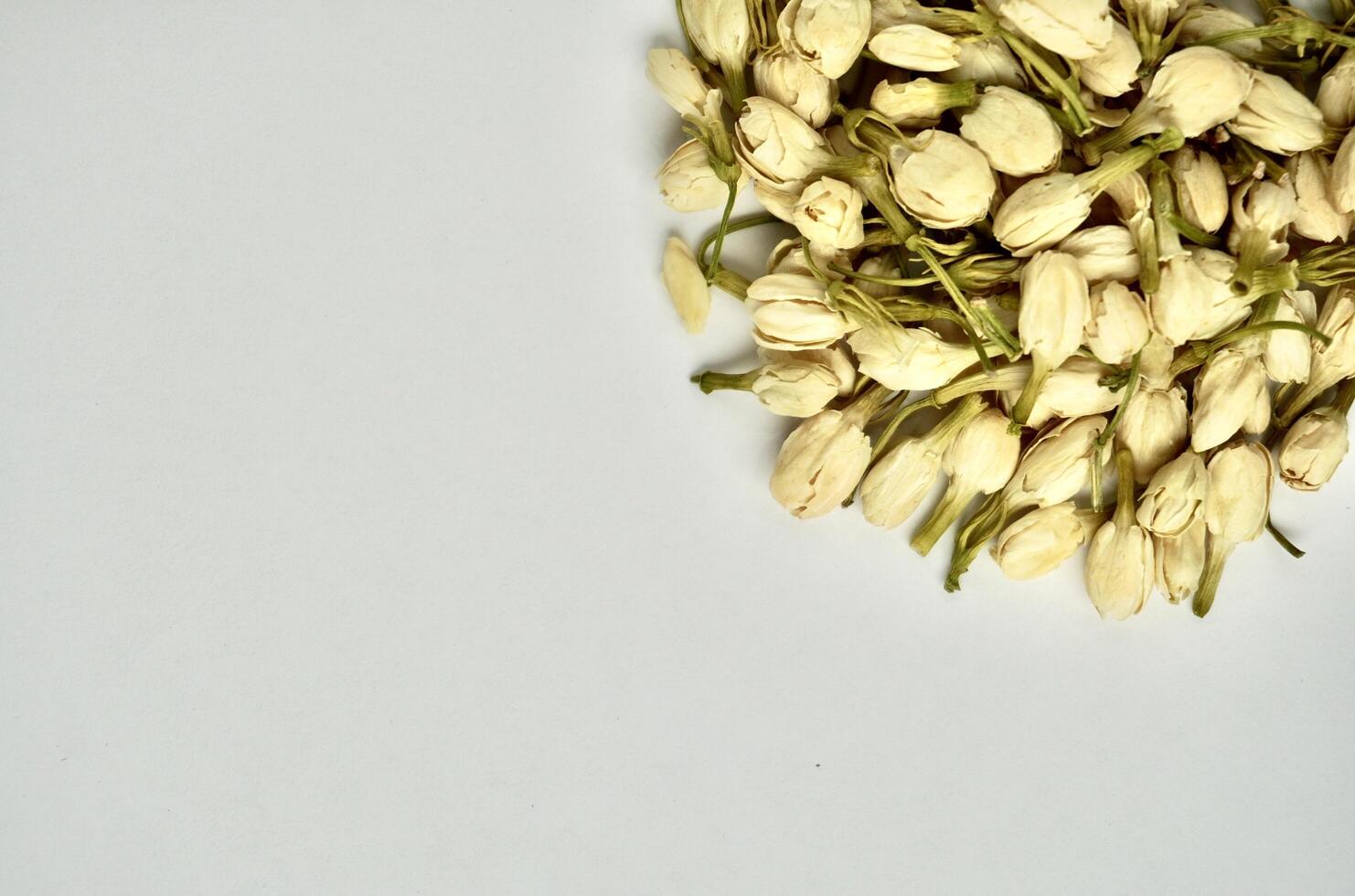Pile of dried jasmine flower buds for aromatheraphy and tea ingredients isolated on horizontal copy spaced plain background. photo