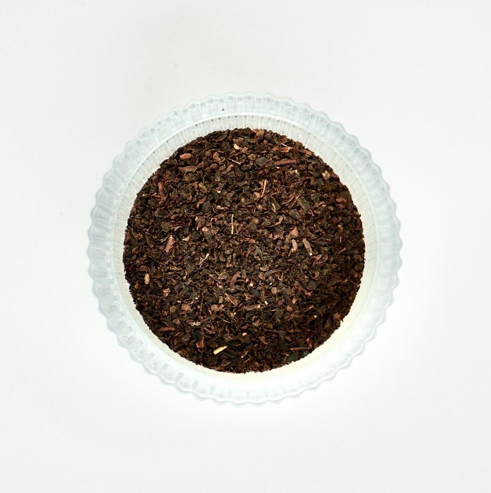 Pile of fragrant earl grey organic tea leaves in round glass bowl isolated on square white background from above angle view. photo