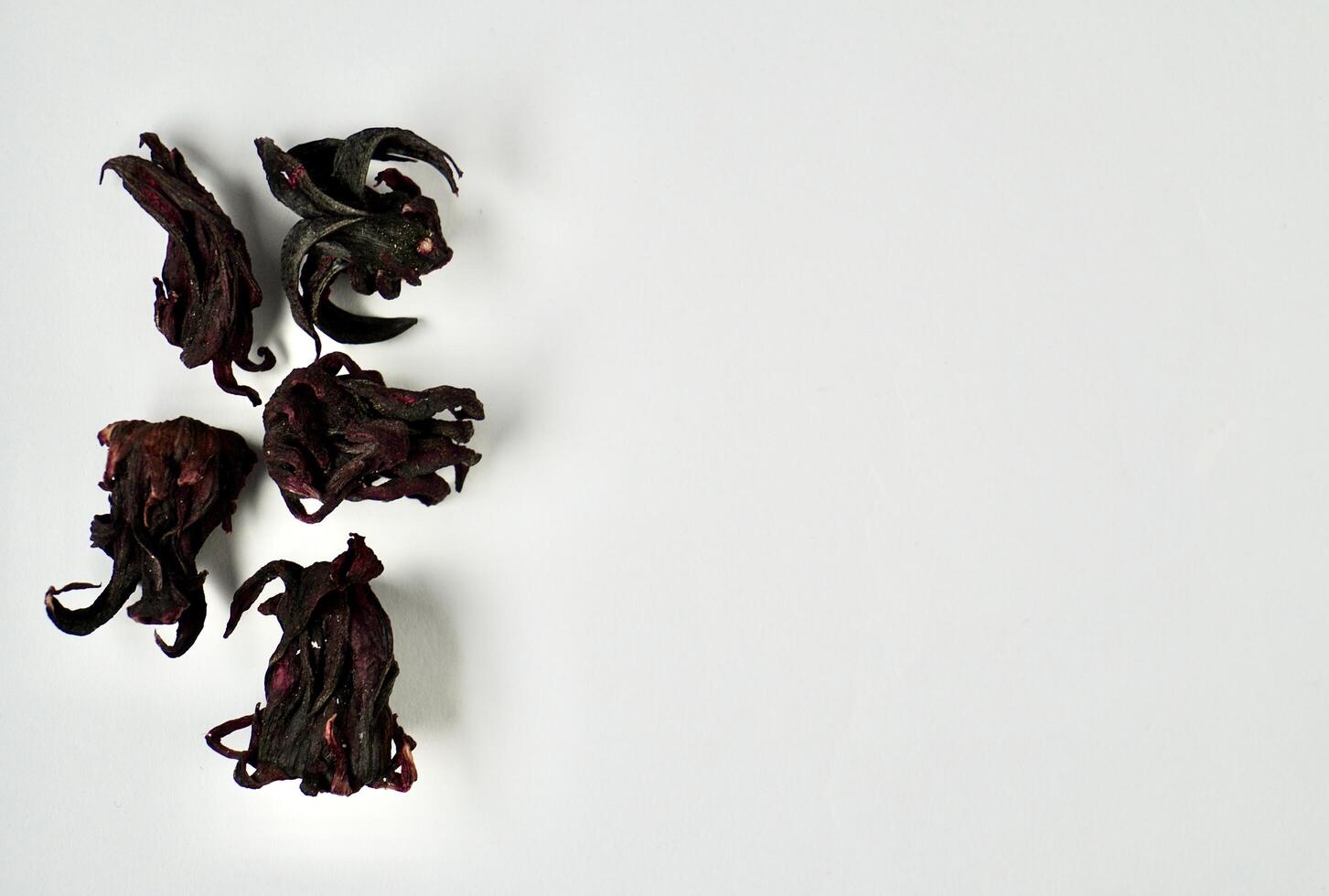 Five pieces of dry purple rosella hibiscus flower herb tea isolated on horizontal copy spaced white background. photo