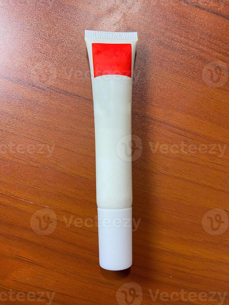 A tube of cream with a red label on top photo