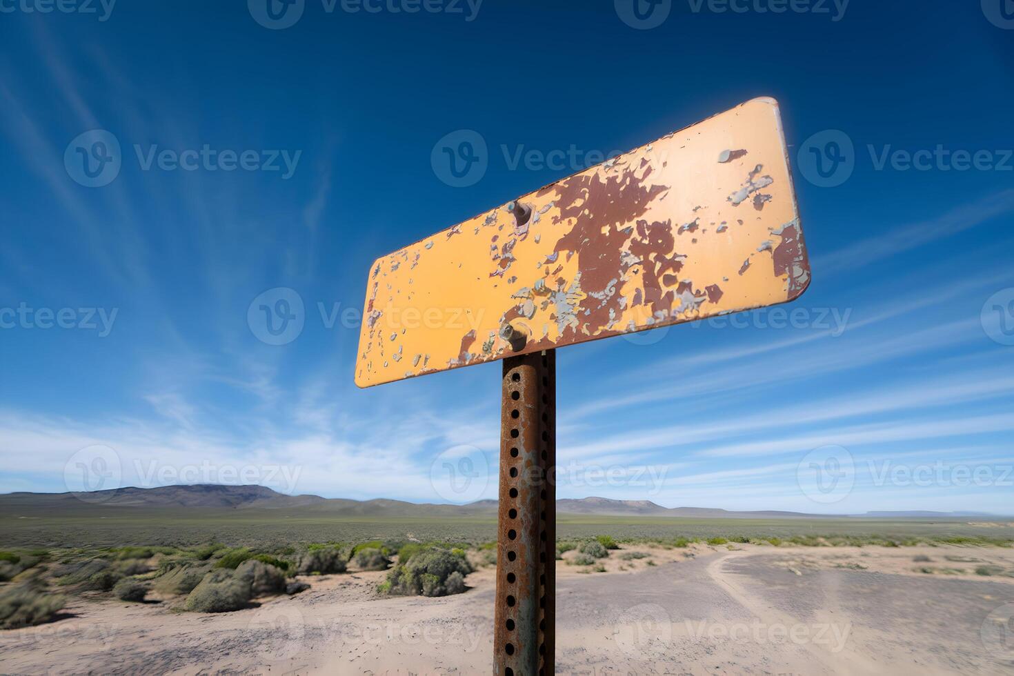A yellow signpost with rust stands tall against a vast blue sky photo