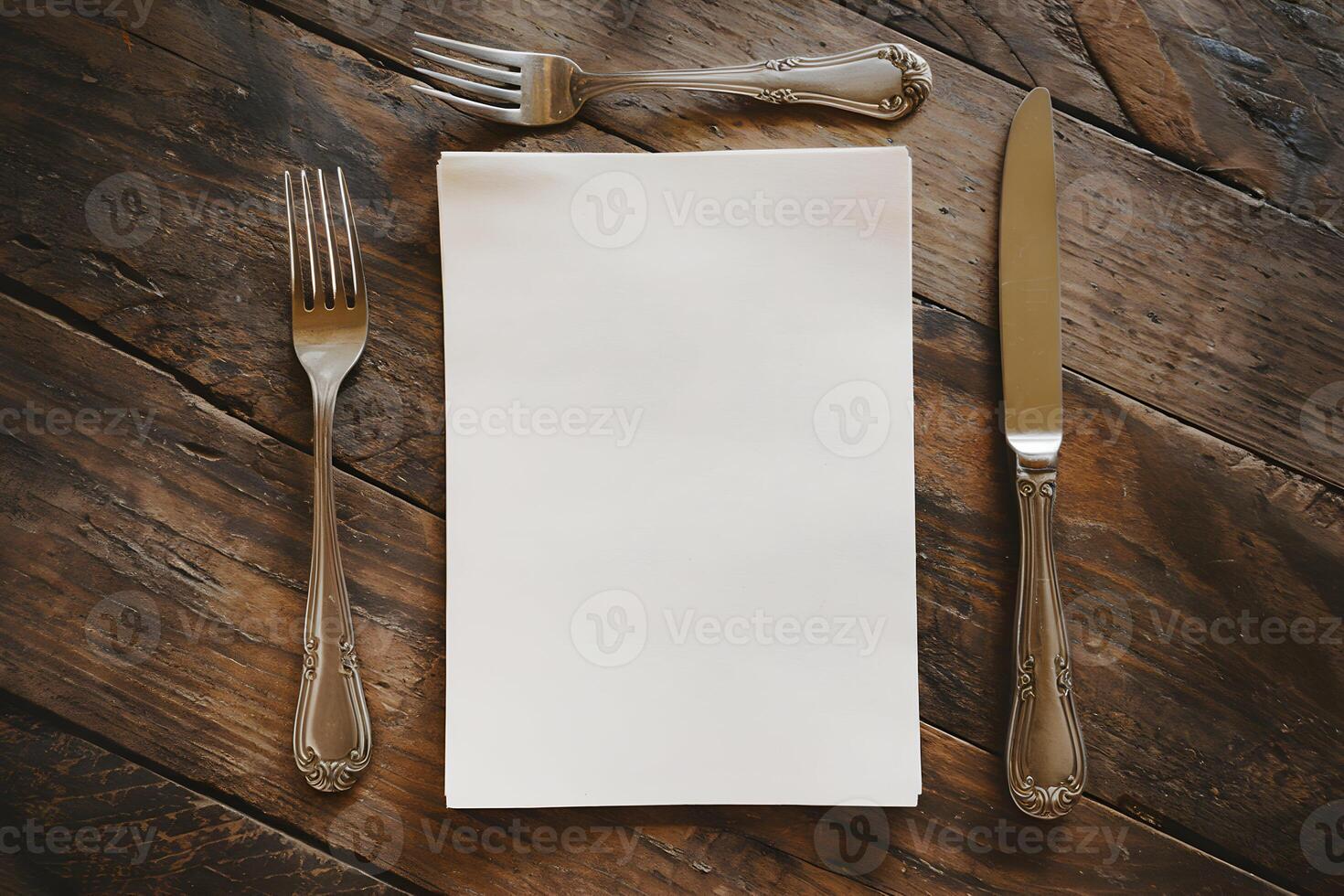 A blank paper lies neatly on a rustic wooden table with silverware photo