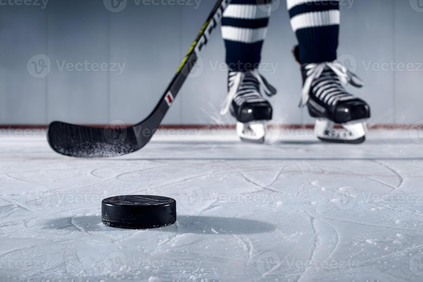 Scuffed black hockey puck rests on icy terrain, with skates and stick nearby photo