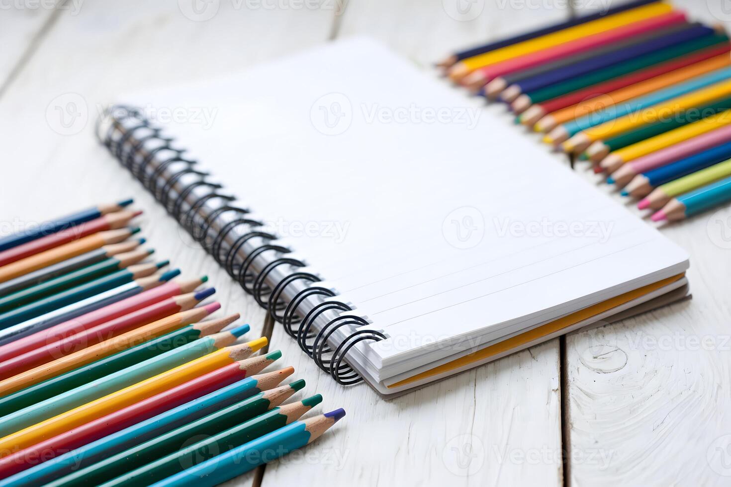 Spiral notebook surrounded by colorful pencils in an artistic, creative environment photo
