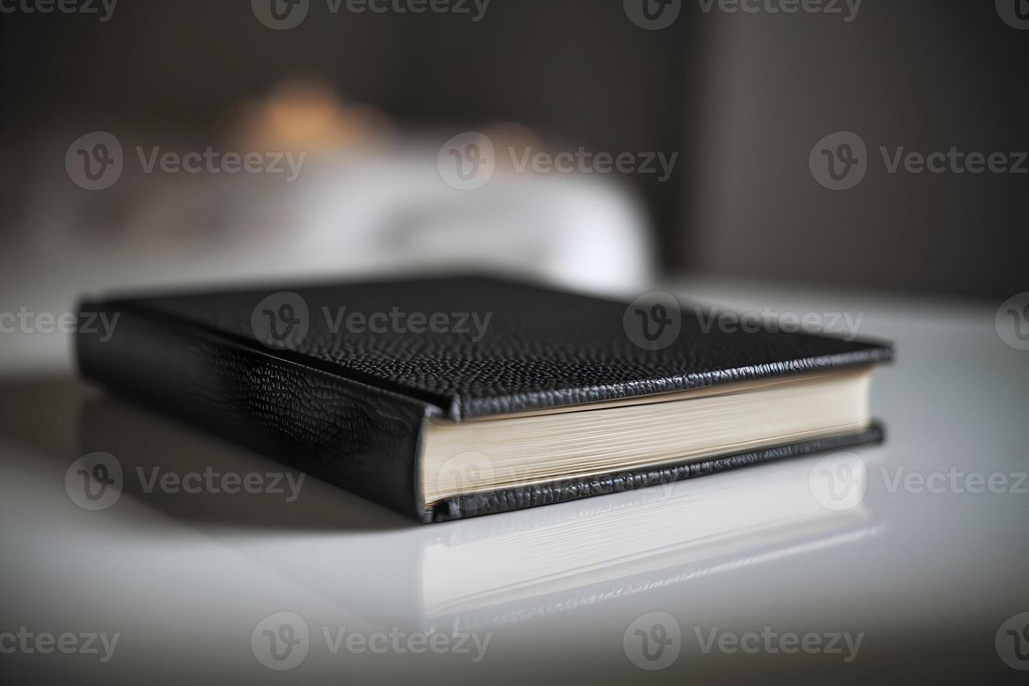 Black book tilted on white surface, textured cover highlighted by subtle light photo