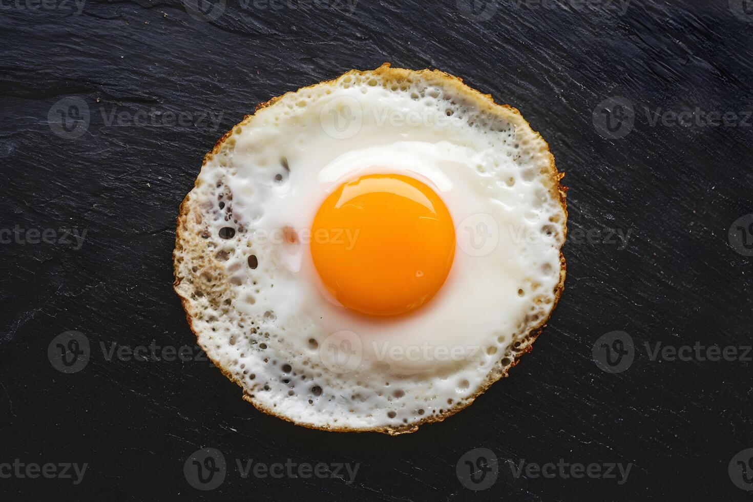 Perfectly fried sunny side up egg on slate surface, golden yolk stands out photo
