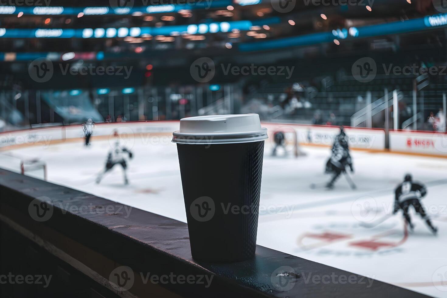 Black coffee cup on ledge overlooking rink, creating cozy stadium atmosphere photo