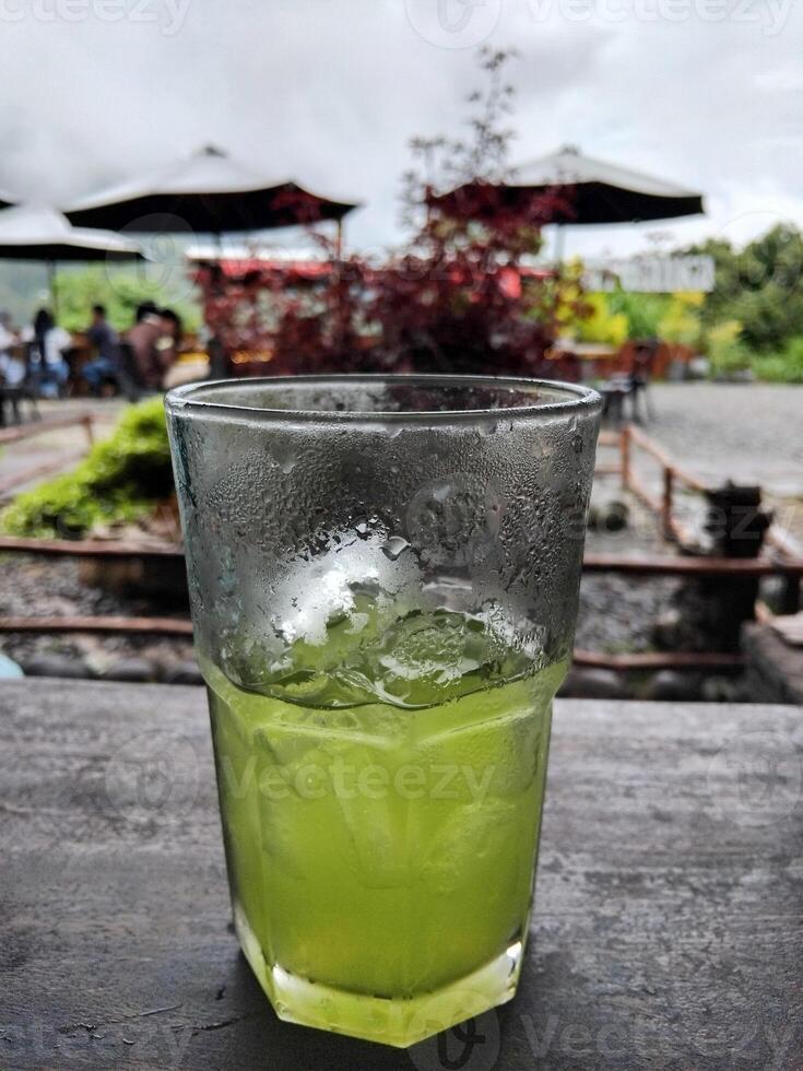 Half a glass of kiwi juice on the table outside the cafe photo