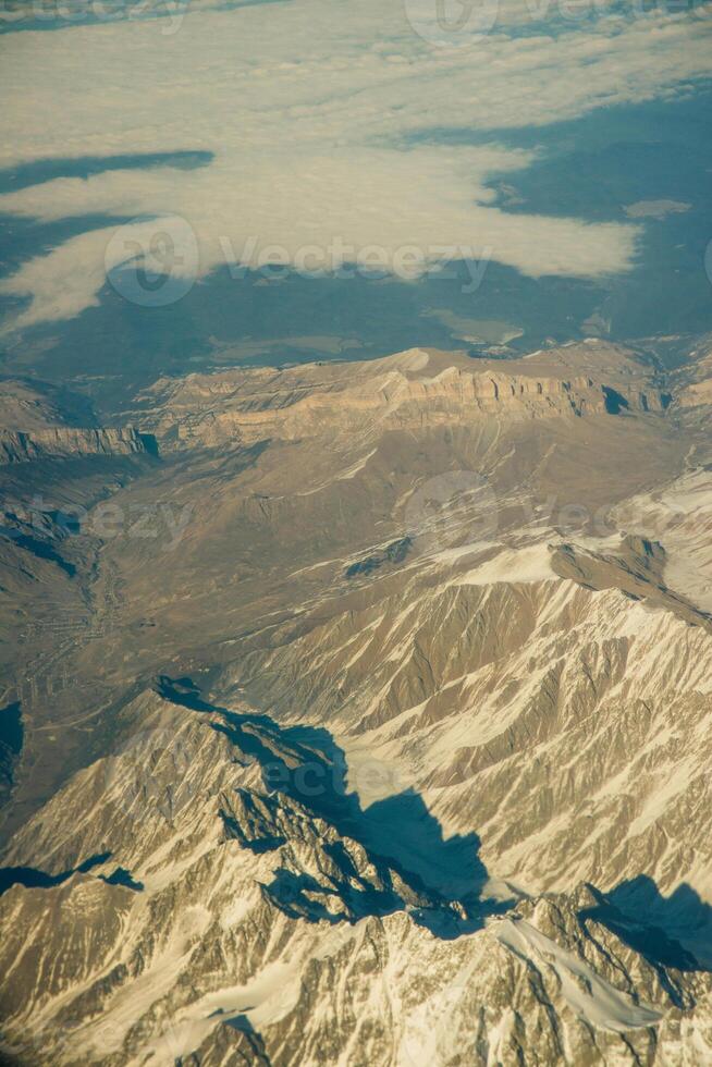 Aerial photo of the landscape with clouds, snowy mountains and view stretching all the way to the horizon