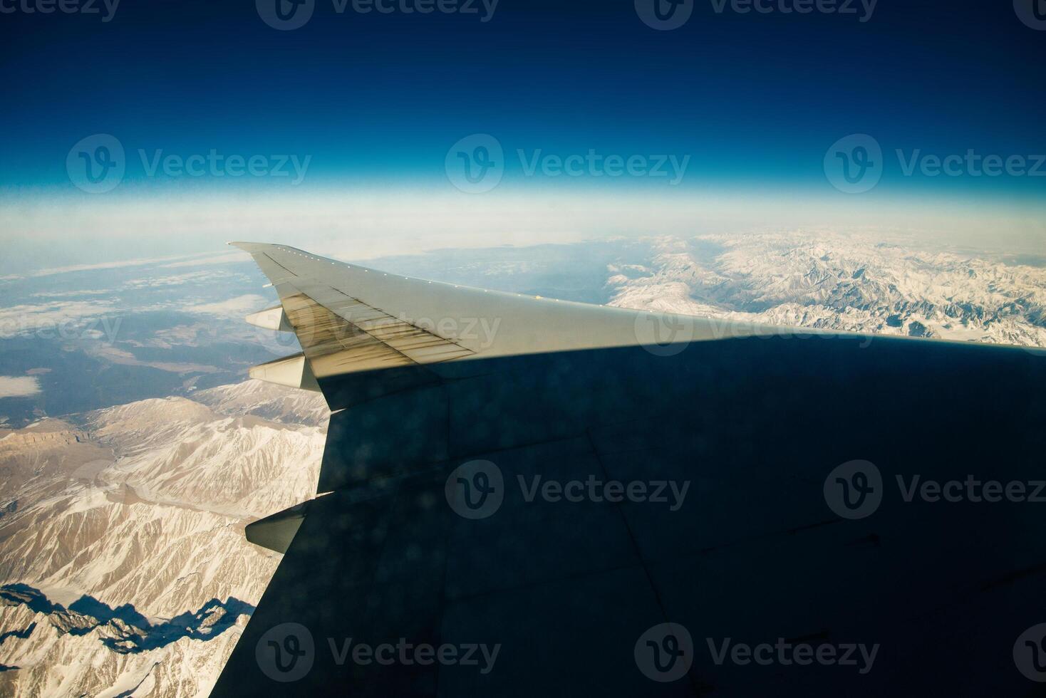 Aerial photo of the landscape with clouds, snowy mountains and view stretching all the way to the horizon