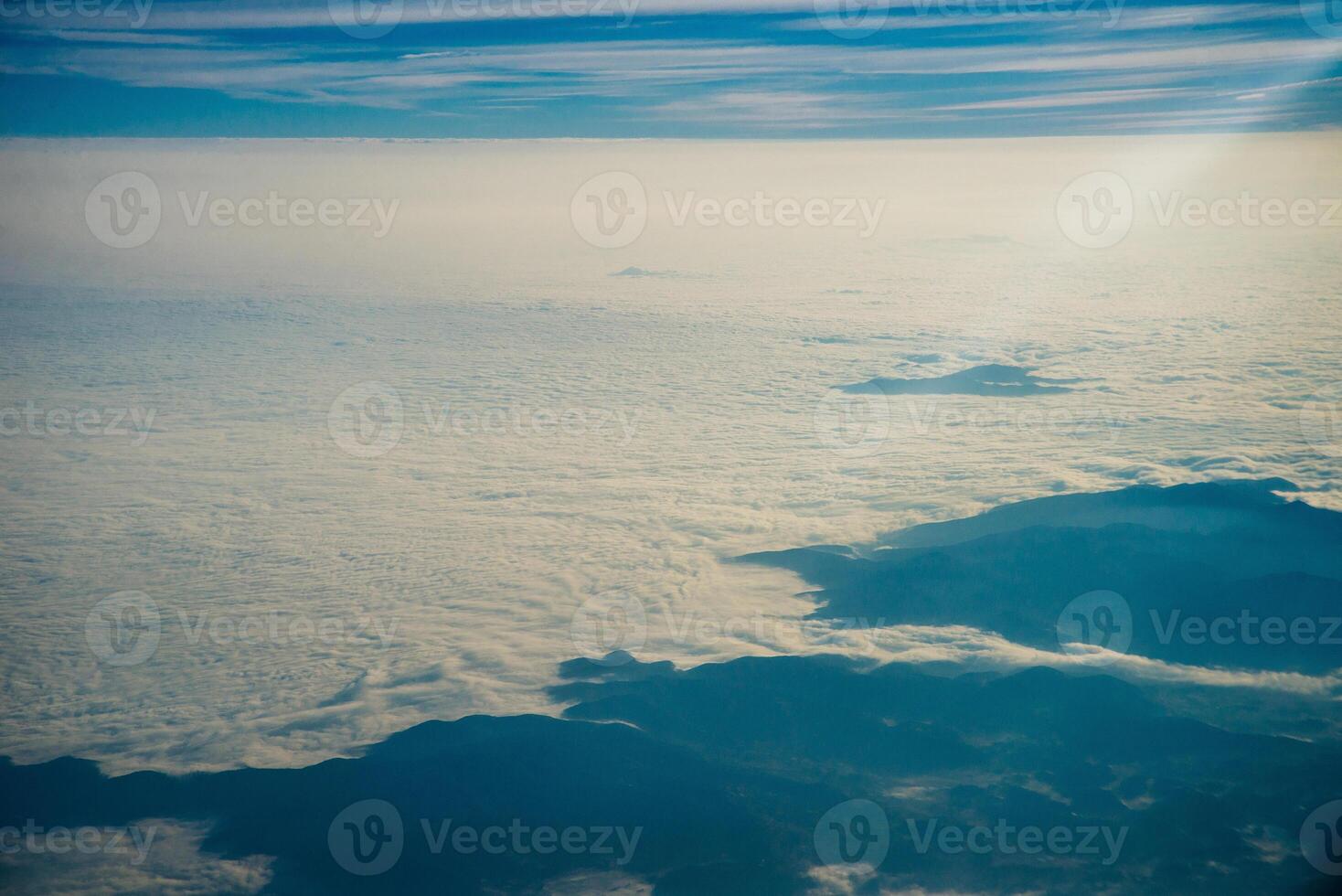 Plane window view of clouds and islands surrounded by sea and airplane wing. Traveling concept photo