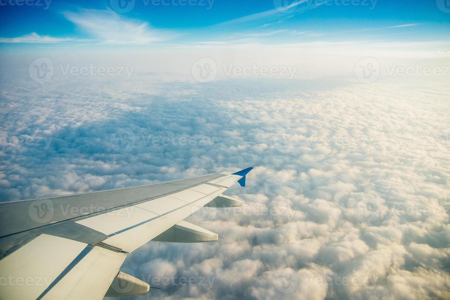 Plane window view of clouds and islands surrounded by sea and airplane wing. Traveling concept photo