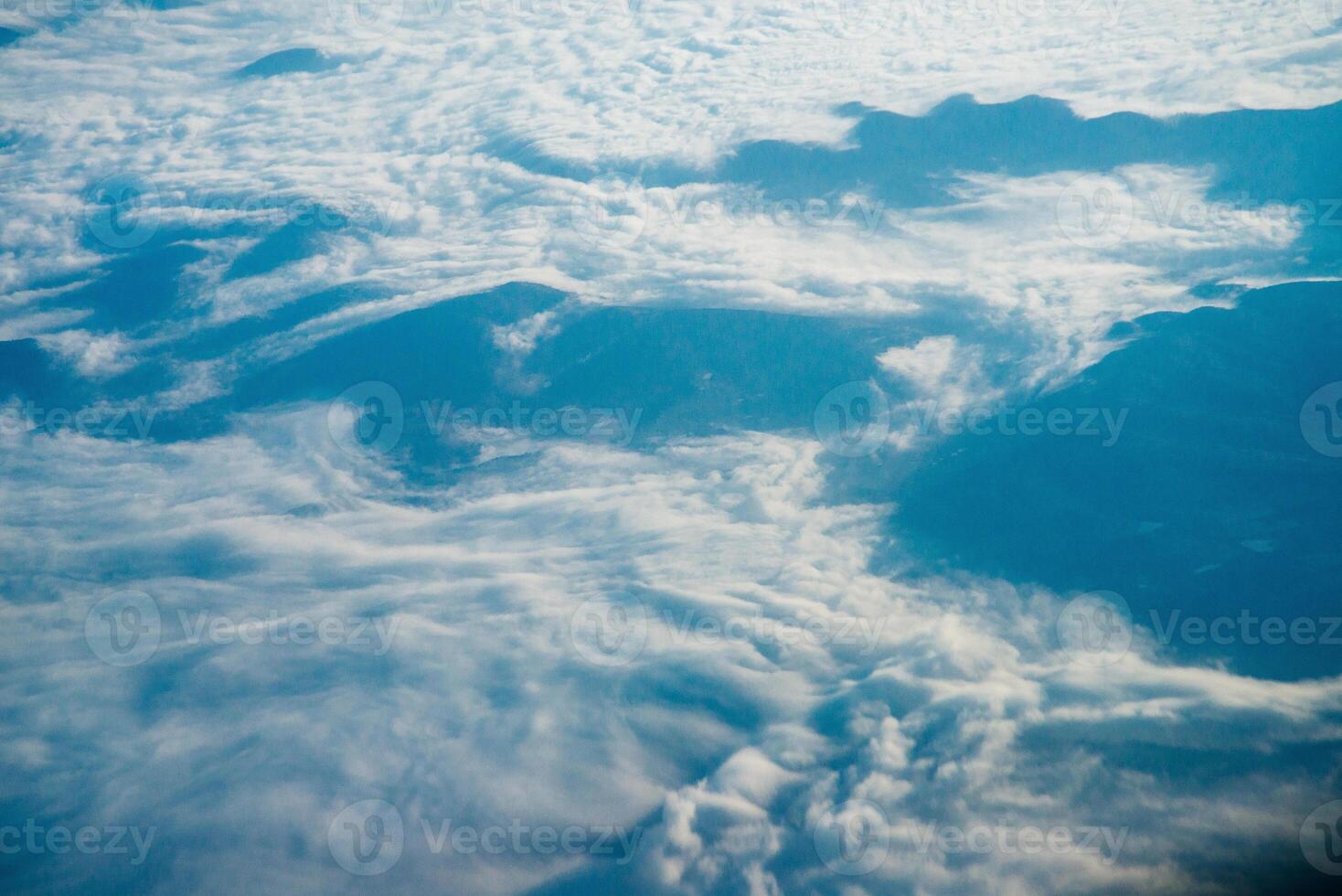 Plane window view of clouds and islands surrounded by sea and airplane wing. Traveling concept photo