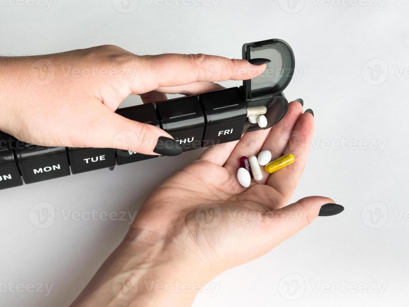 Organizing weekly medication in hands with pill organizer for health and wellness photo