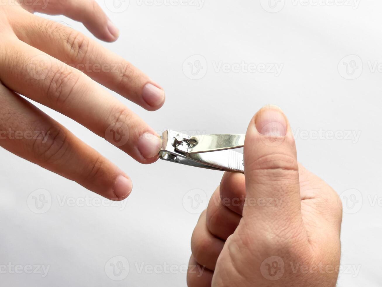 Close up of hands trimming fingernails with nail clipper on white background photo