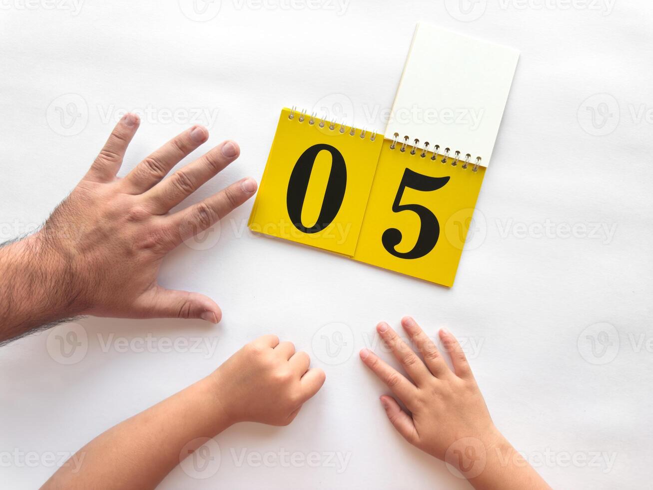 Adult and child hands counting with calendar showing number five on white background photo