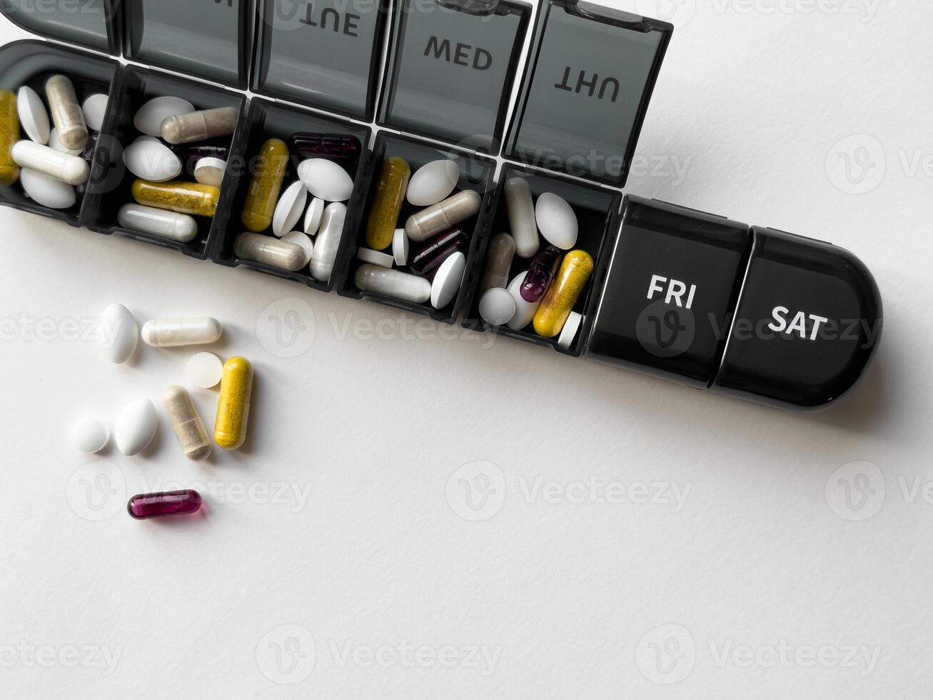 Weekly pill organizer with mixed medication on white background photo