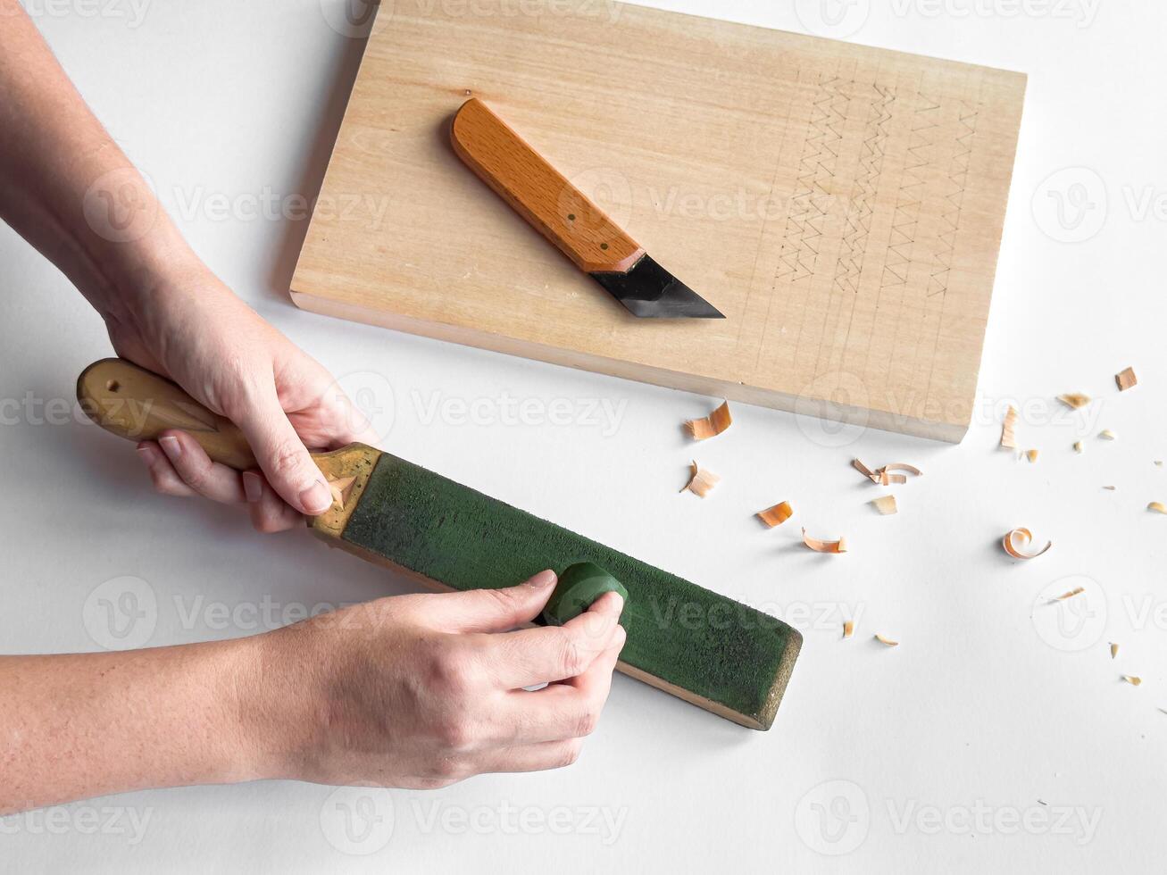Hands sharpening tool with strop next to cutting board and carving knife photo
