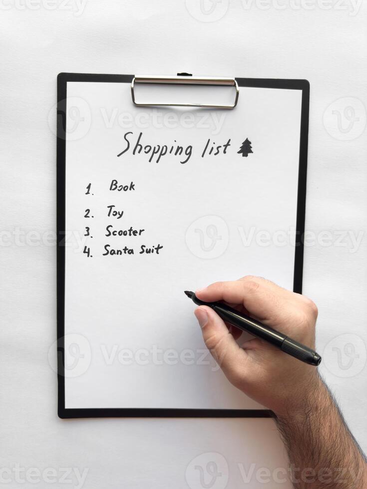 Hand writing a shopping list on clipboard with pen photo