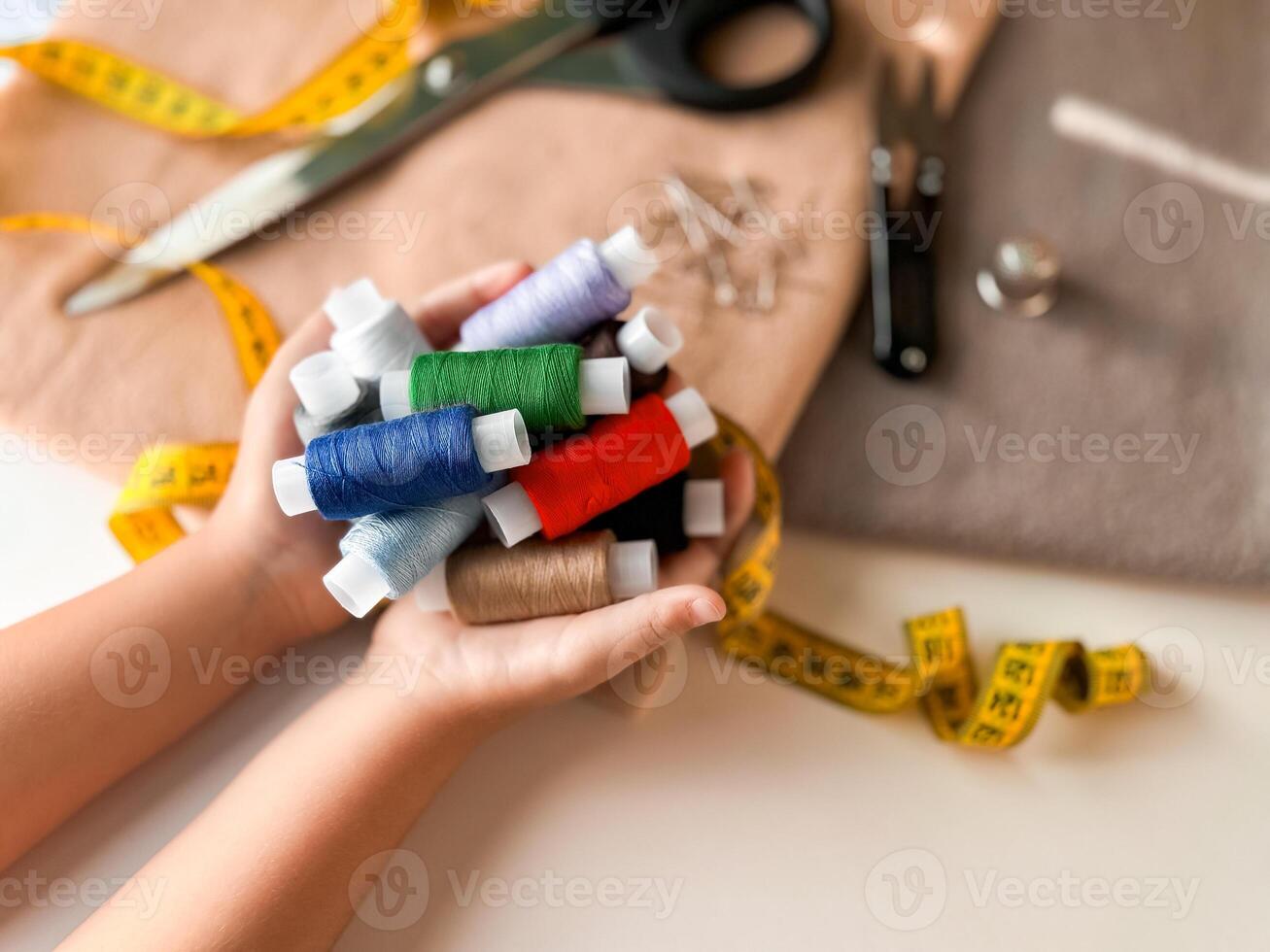 Crafting essentials. Hands holding colorful spools of thread with sewing tools photo