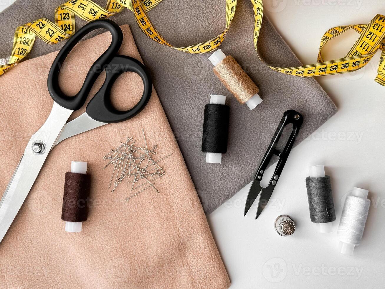 Sewing essentials with scissors, measuring tape, and thread on fabric photo