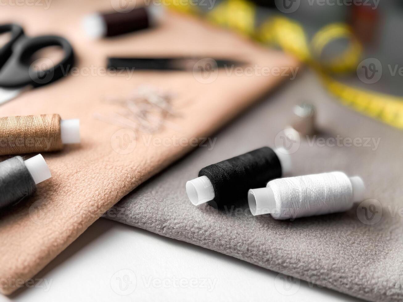 Sewing essentials with thread spools, needles, and measuring tape on fabric background photo