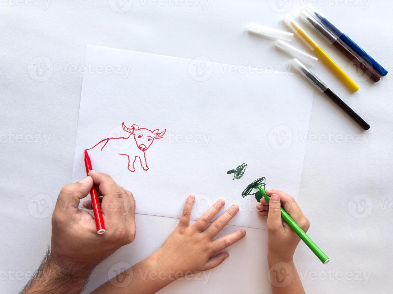 Father and child create animal drawing together using vibrant markers photo