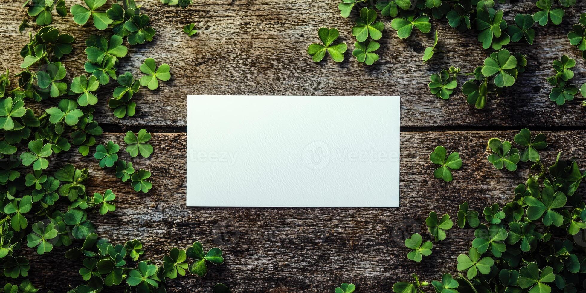 Rustic wooden background with blank white card and green clover leaves for nature themed designs photo