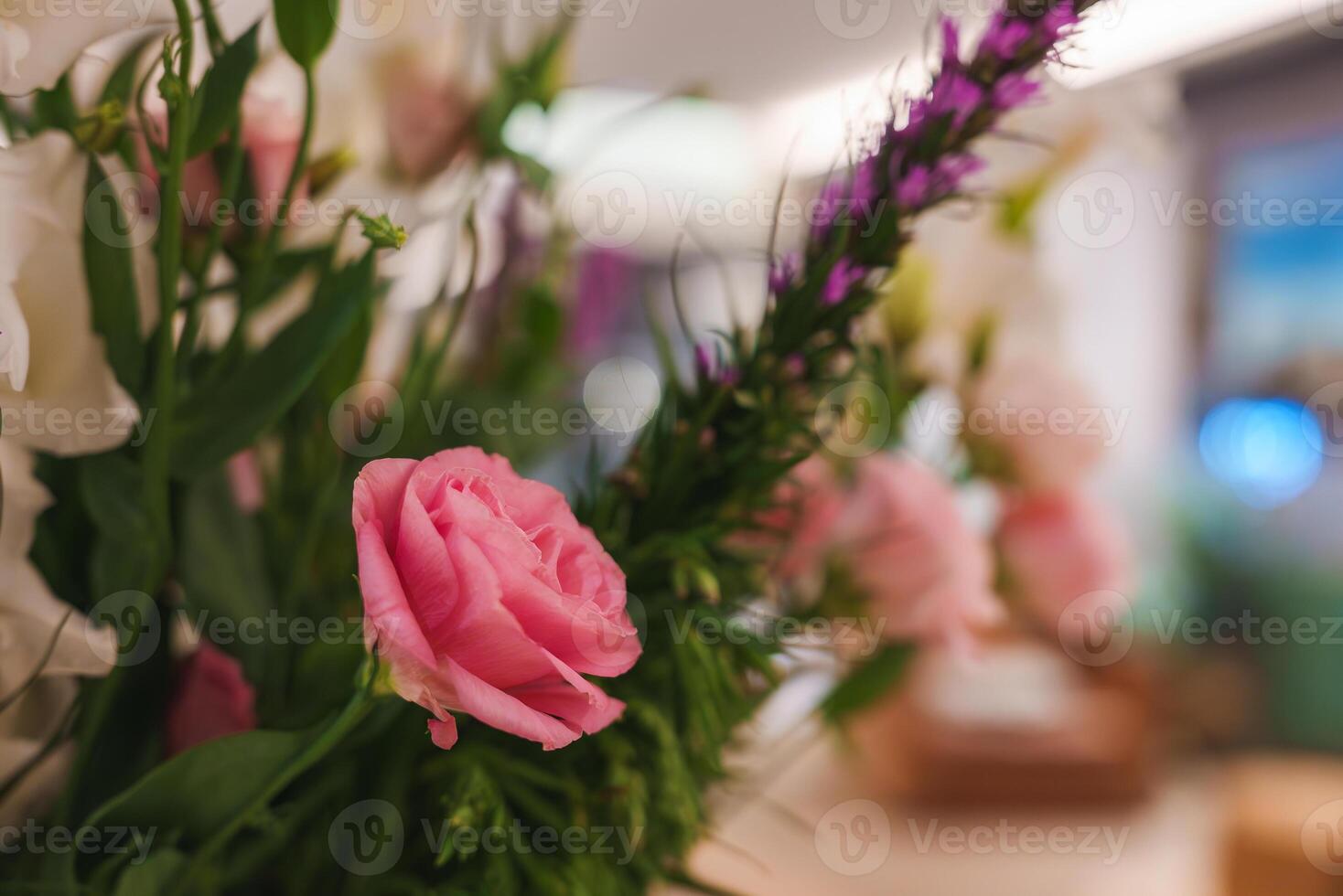 Close Up of Pink Rose in Lush Floral Arrangement with Green Foliage photo