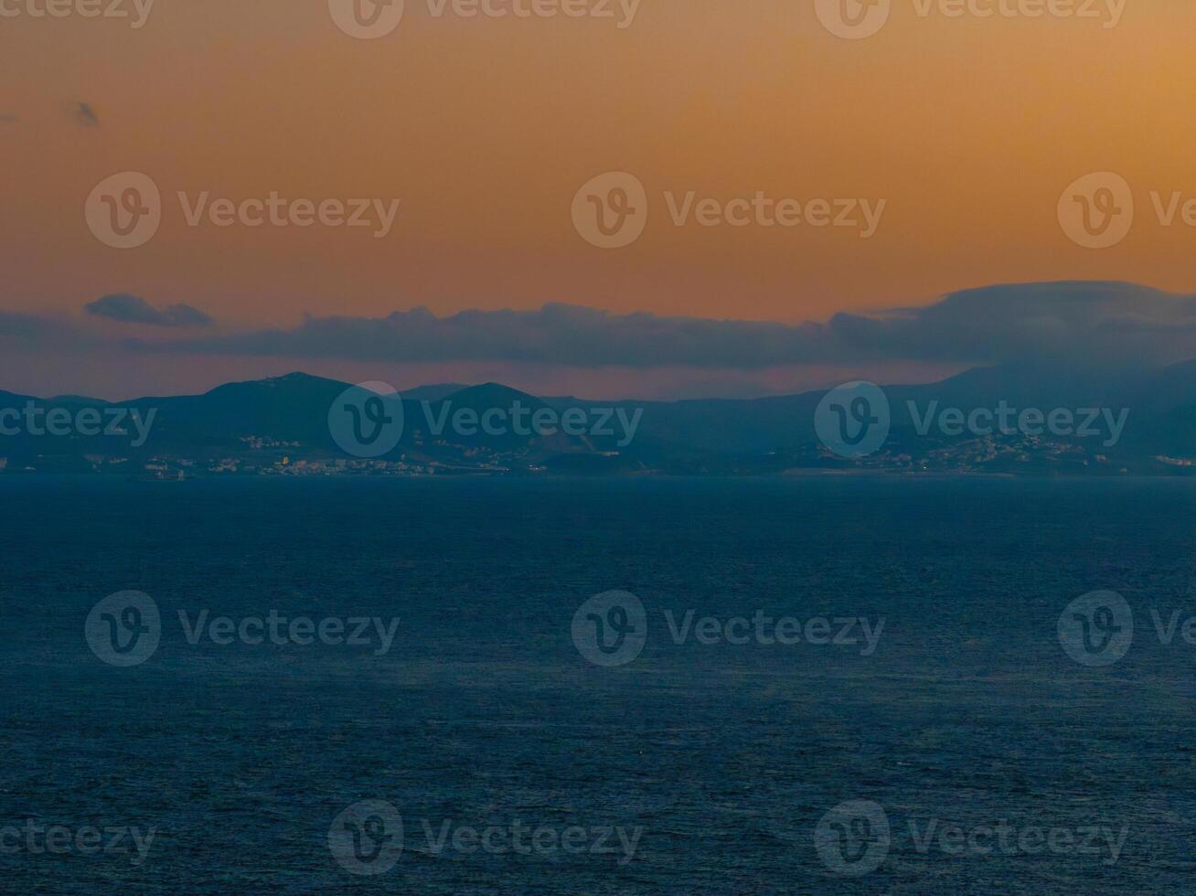 Sunset Over the Sea with Tarifa Town Silhouette in Spain photo