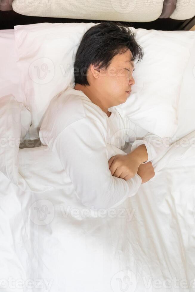 Top view of an exhausted man tosses and turns on a bed all night by restless sleep or insomnia problem. Health issue from anxiety, depression, and stress. photo
